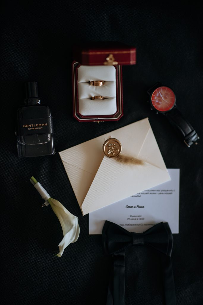 Real flat lay photograph of wedding rings, invitation and formal accessories