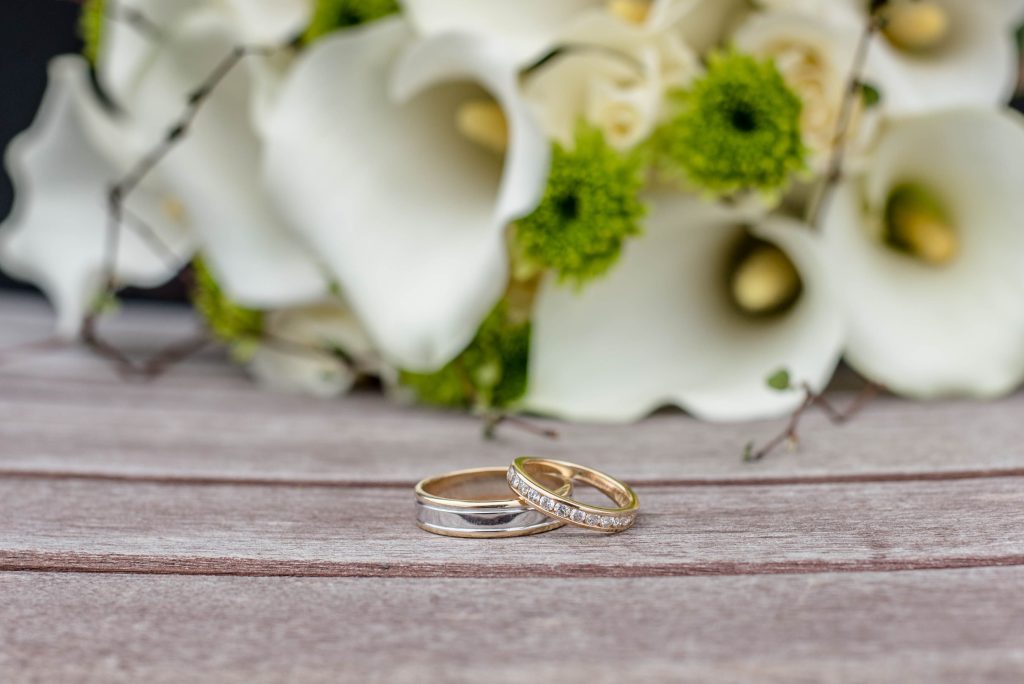 Real photograph of wedding rings beside white flowers